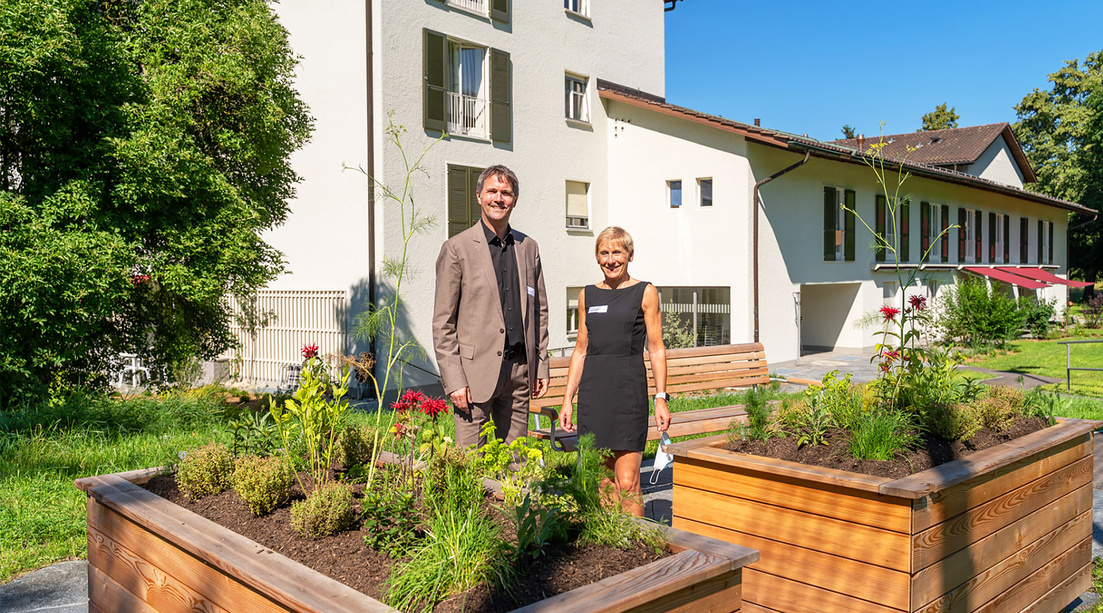 Caspar Hoesch, Bereichsleiter Bau&Entwicklung, und Andrea Martin-Fischer, Direktorin, vor den neu eingerichteten Hochbeeten in der Siedlung Espenhof Süd, die von den Mieterinnen und Mietern selbst bepflanzt werden können.